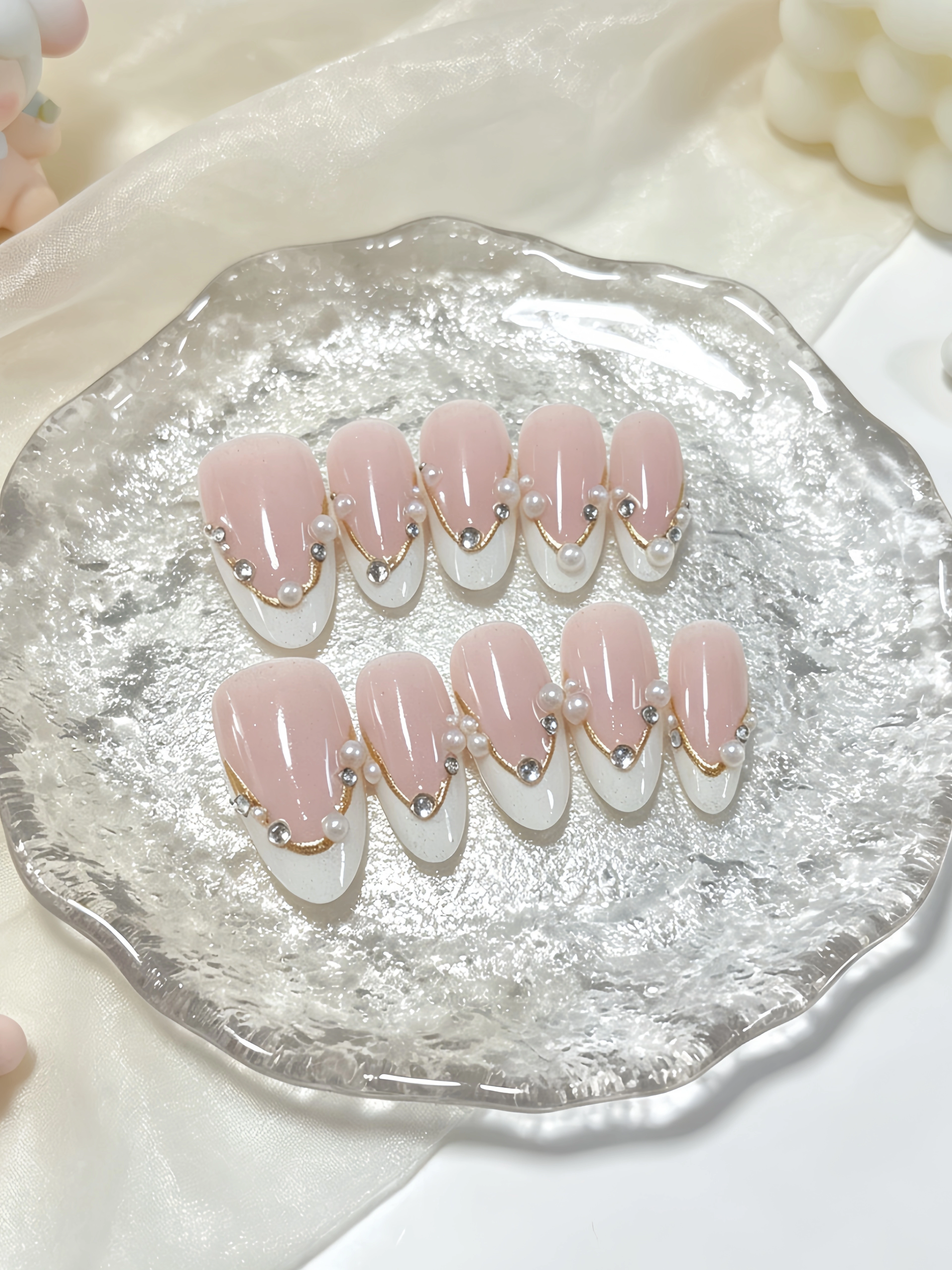 10 ongles courts en forme d'amande, aux couleurs principales rose nude et blanc laiteux, dans un sty