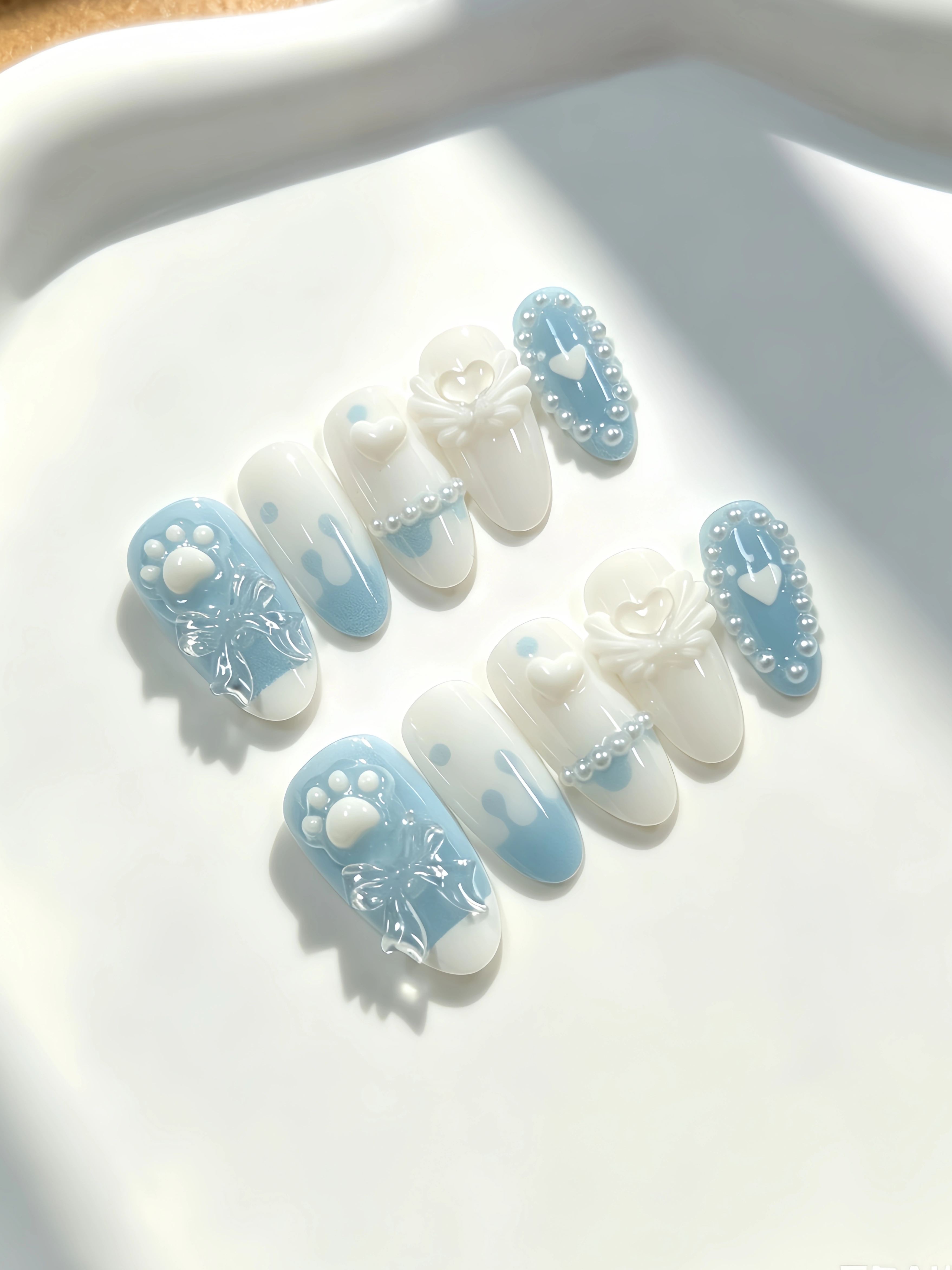 10 ongles de longueur moyenne en forme d'amande, aux couleurs principales blanc laiteux et bleu clai