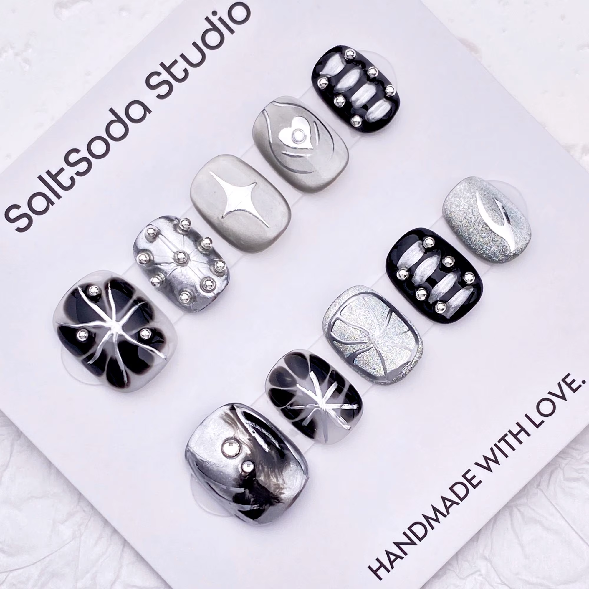 Ongles press-on faits main sur le thème des étoiles gothiques ; style "sweet-meets-cool" avec des strass et des accents métalliques