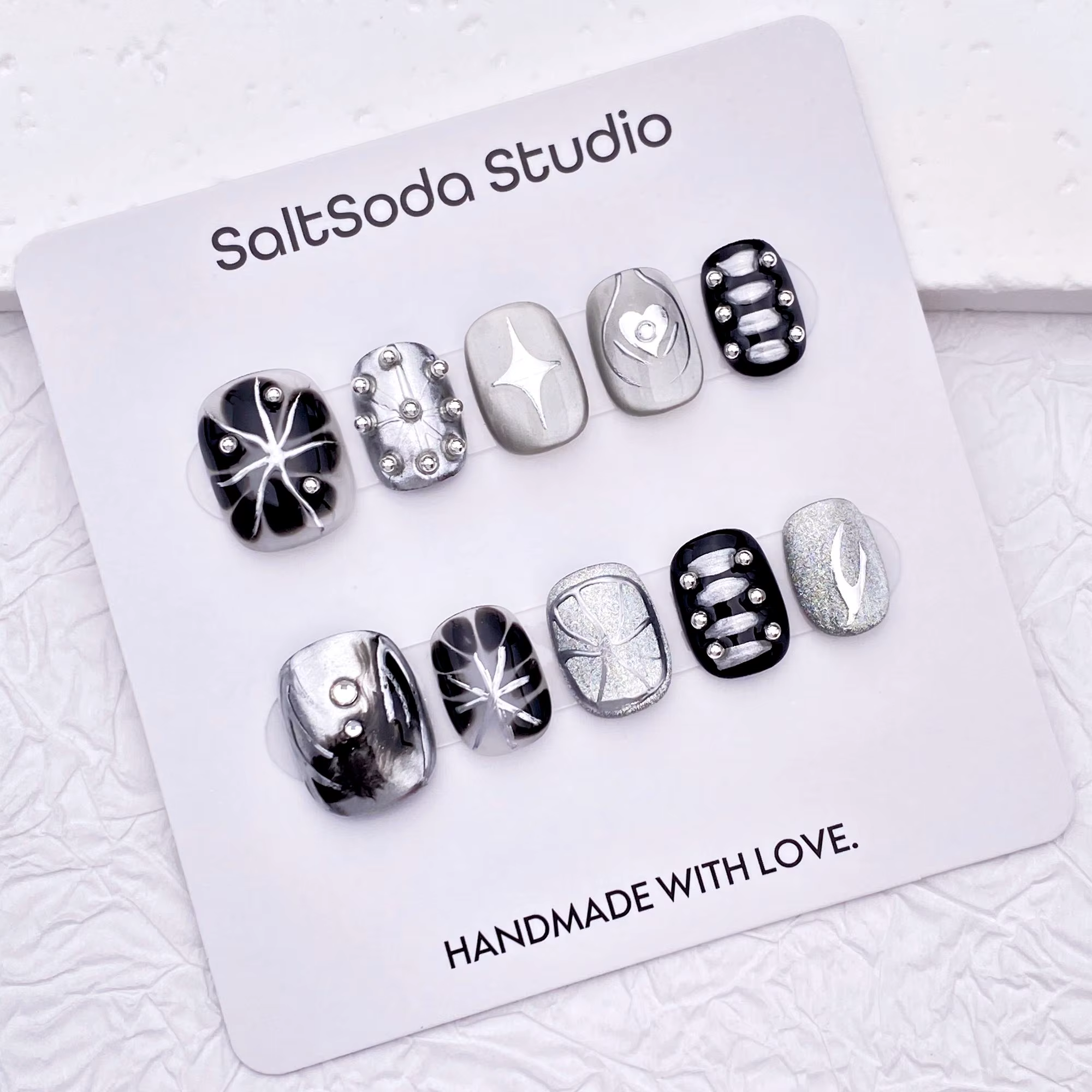 Ongles press-on faits main sur le thème des étoiles gothiques ; style "sweet-meets-cool" avec des strass et des accents métalliques