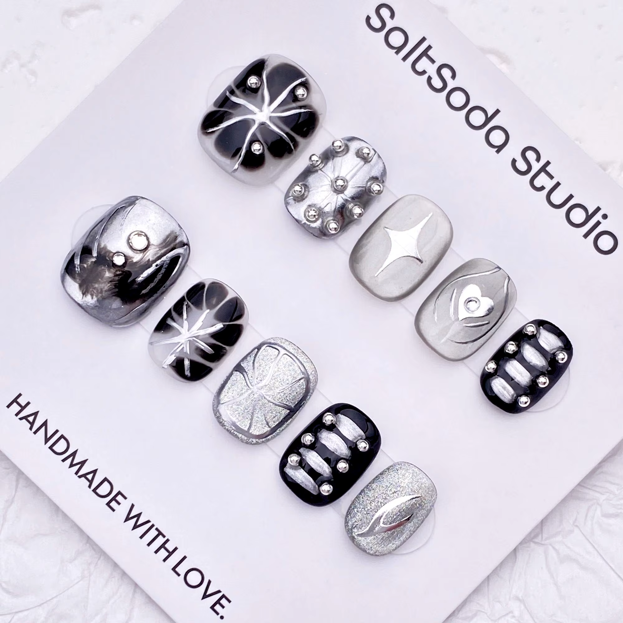 Ongles press-on faits main sur le thème des étoiles gothiques ; style "sweet-meets-cool" avec des strass et des accents métalliques